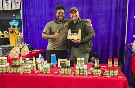 Two people standing behind a Trueheart's Blend display filled with spice jars