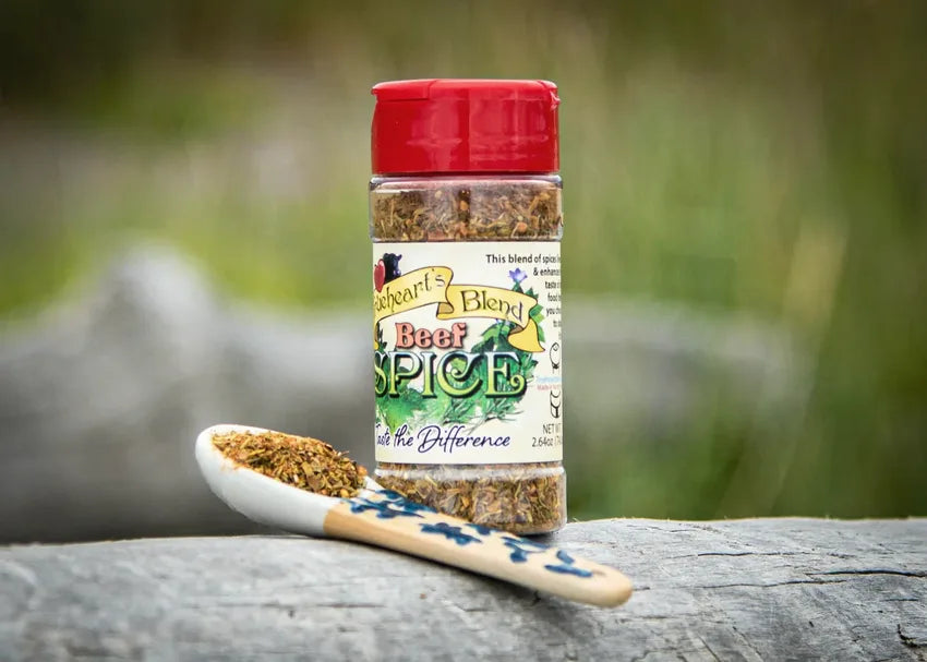 Seasoning for Beef jar with a spoonful of the blend on weathered wood outdoors
